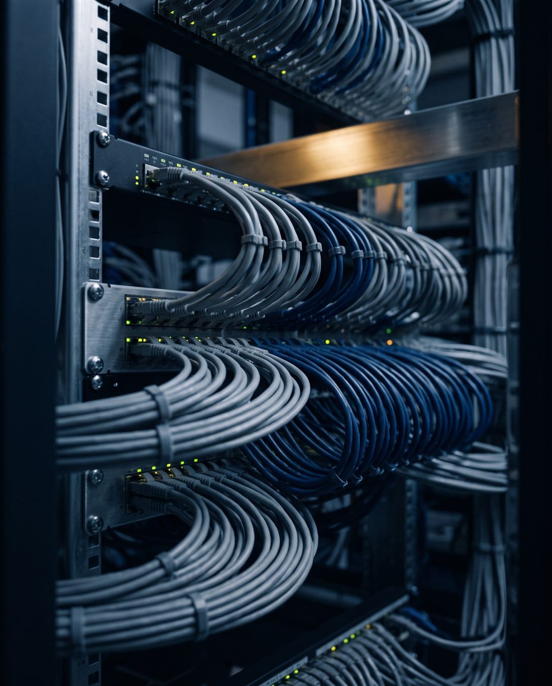 A close view of a network patch panel, ethernet cabling combed into disciplined parallel runs with link indicators lit.